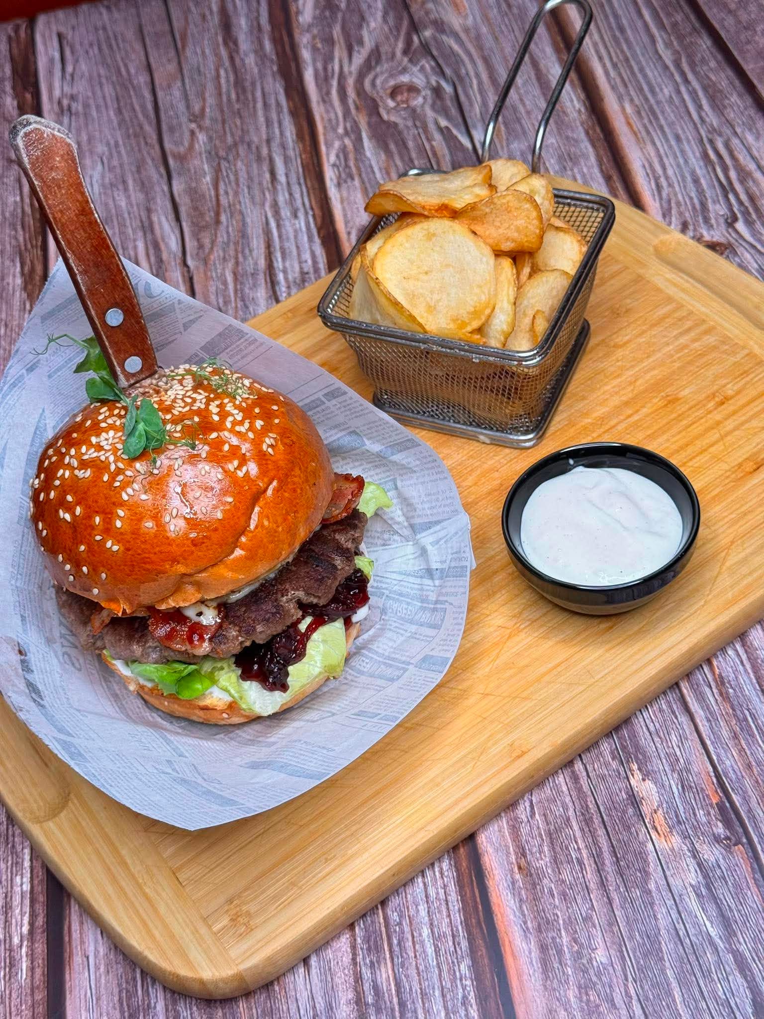Bohém burger - buci, marhahúspogácsa, citrusos majonéz, grillezett camembert, áfonyás lilahagyma chutney, római saláta, sült bacon - chipsburgonyával és citrusos majonézzel szervírozva
